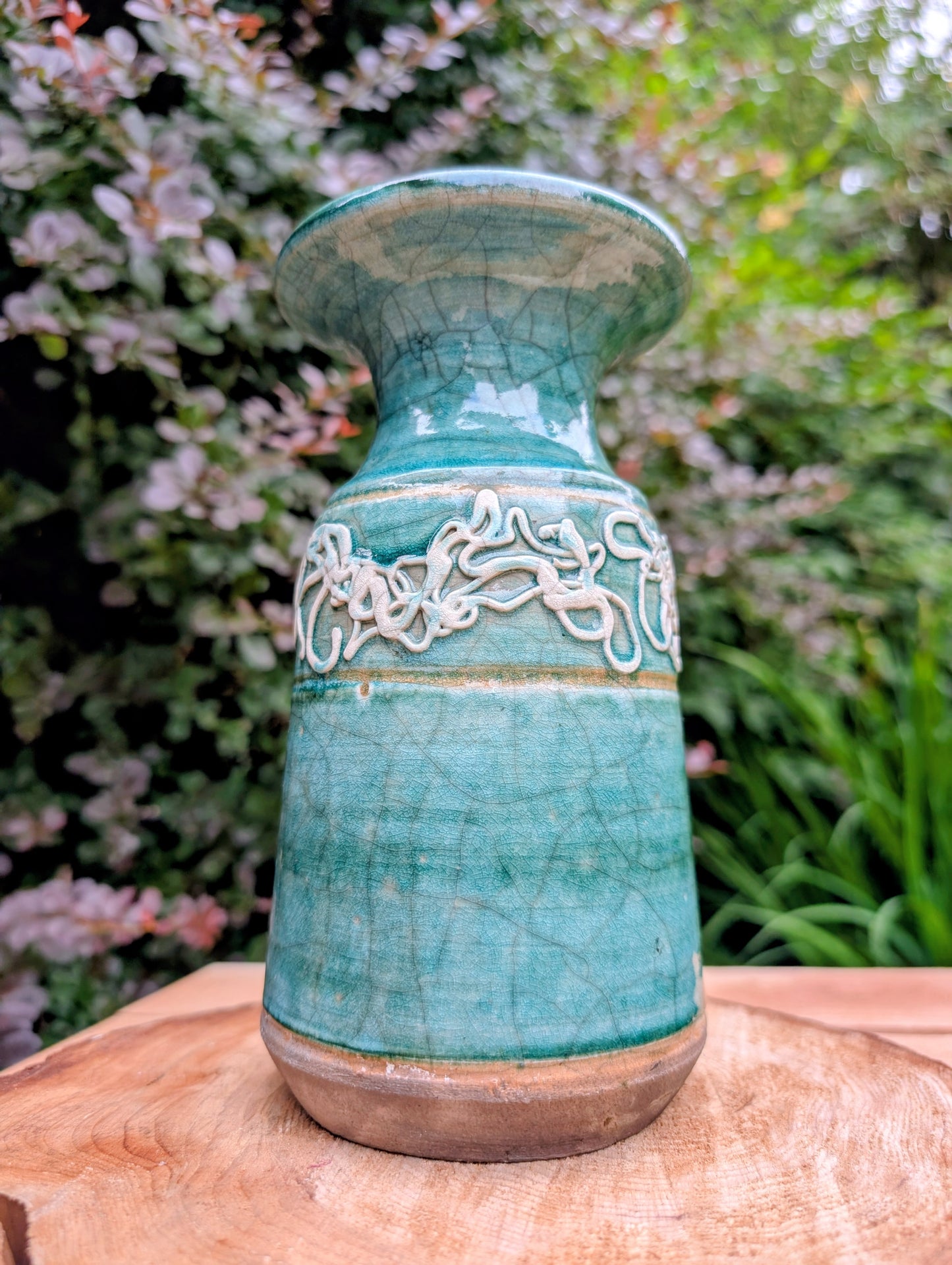 Celebrate the artistry of 1970s studio ceramics with this signed and dated handmade stoneware vase. Finished in a rich teal crackle glaze with distinctive white applied slip decoration, this sculptural piece brings timeless character to shelves, tables, and curated collections.