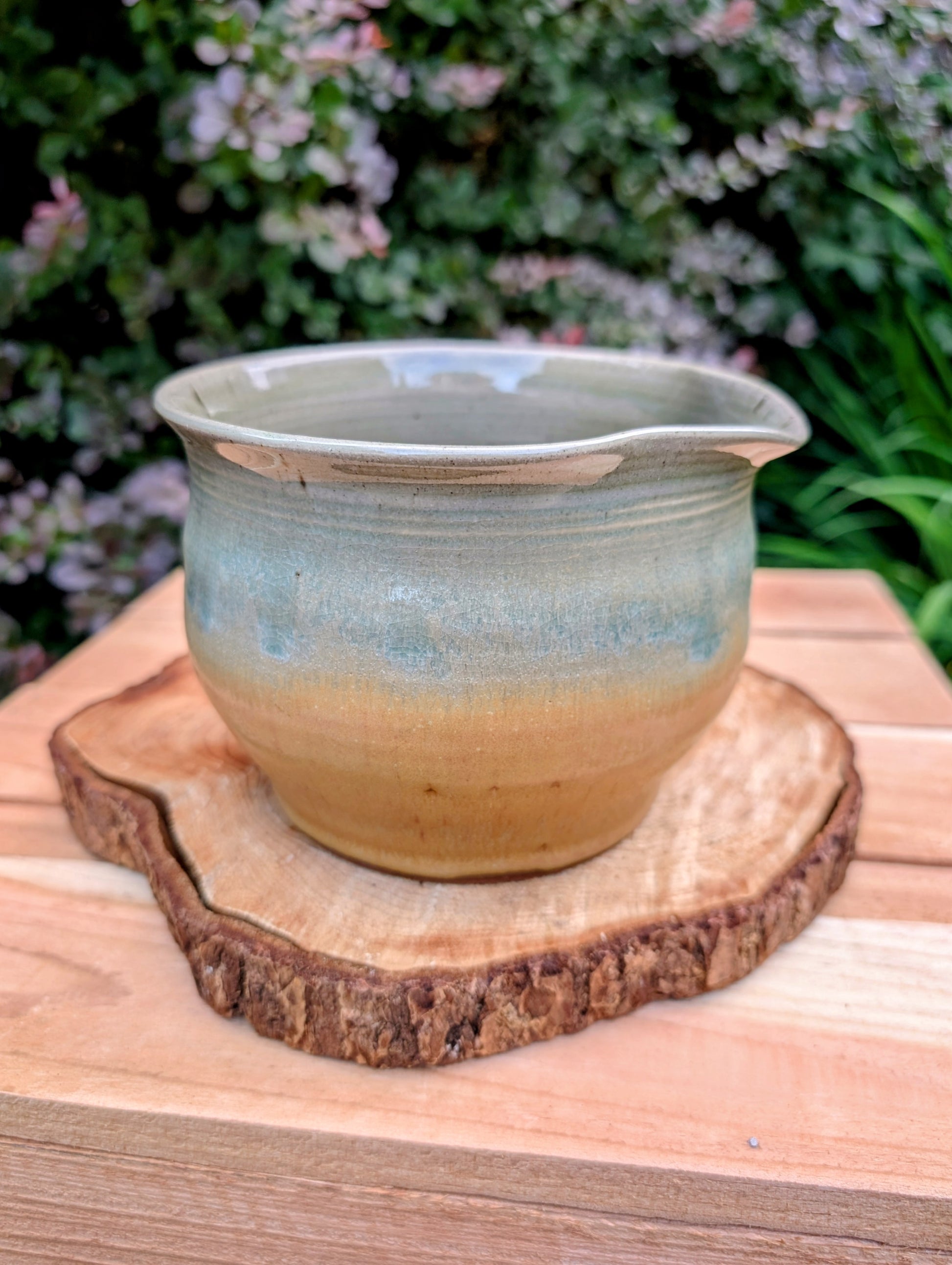 A beautifully hand-thrown studio pottery pouring bowl featuring a soft blue-green celadon glaze over warm buff stoneware. Equally suited for serving, light kitchen use, or display, this artisan-made piece celebrates the beauty of handcrafted ceramics and timeless functional design.