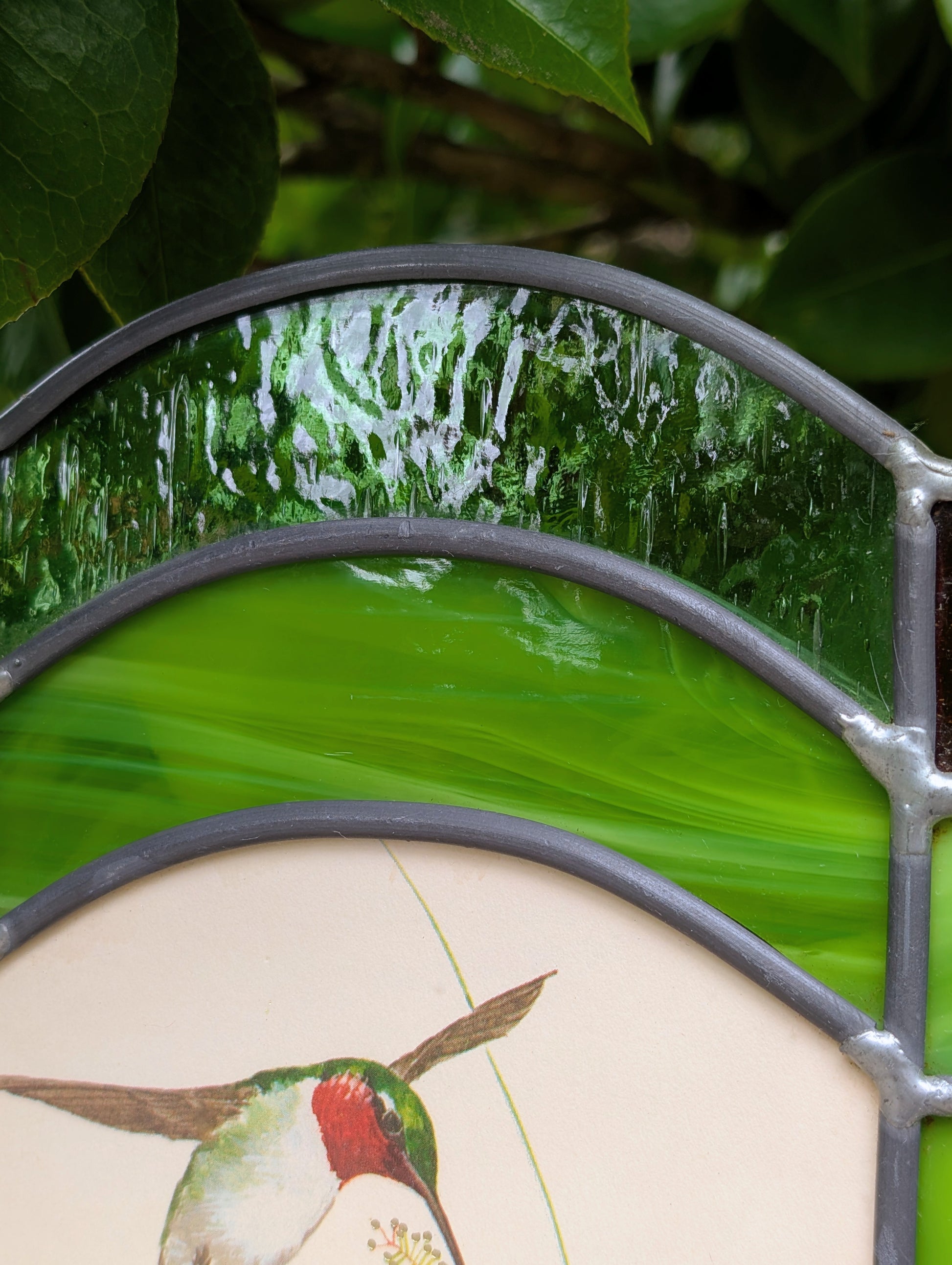 Bring the beauty of a hummingbird in bloom into your home with this handcrafted stained glass hanging panel. Featuring vibrant textured art glass surrounding a detailed hummingbird and hibiscus centerpiece, it catches natural light beautifully and adds year-round color to any window, sunroom, or garden-inspired space.
