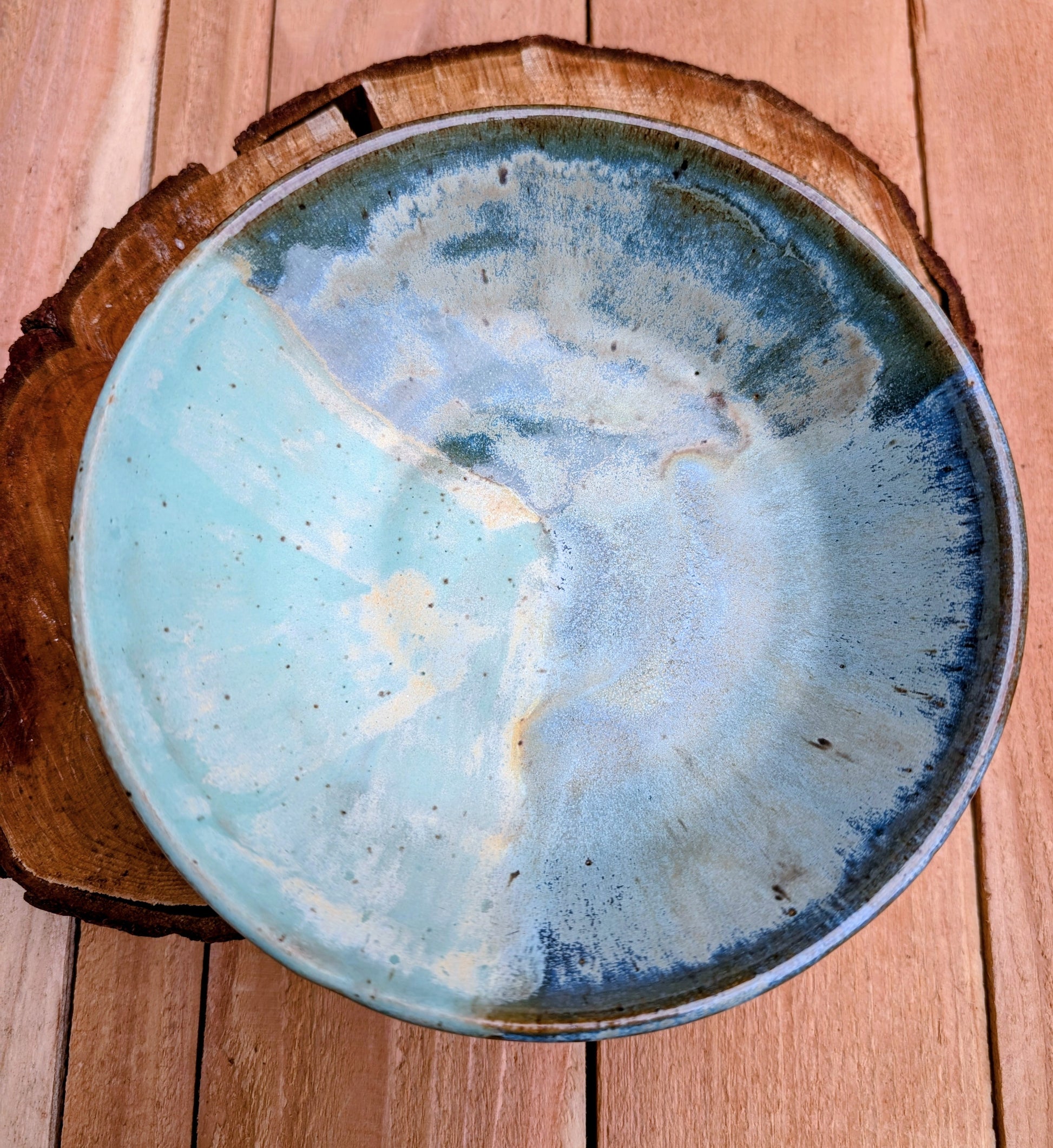 Bring the calming colors of the Pacific Northwest into your home with this handcrafted studio pottery bowl. Featuring layered blue, aqua, cream, and olive reactive glazes, this artisan stoneware piece is equally beautiful as a serving bowl or decorative display.