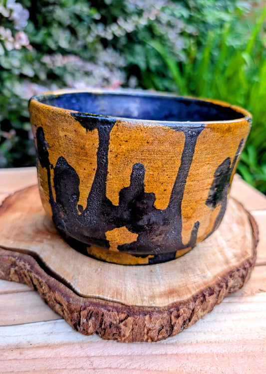 A beautifully hand-thrown studio pottery bowl featuring a rich cobalt blue interior, earthy ochre exterior, and expressive black drip glaze. Its timeless craftsmanship and organic design make it equally suited for serving, display, or adding artisan character to any Pacific Northwest-inspired home.