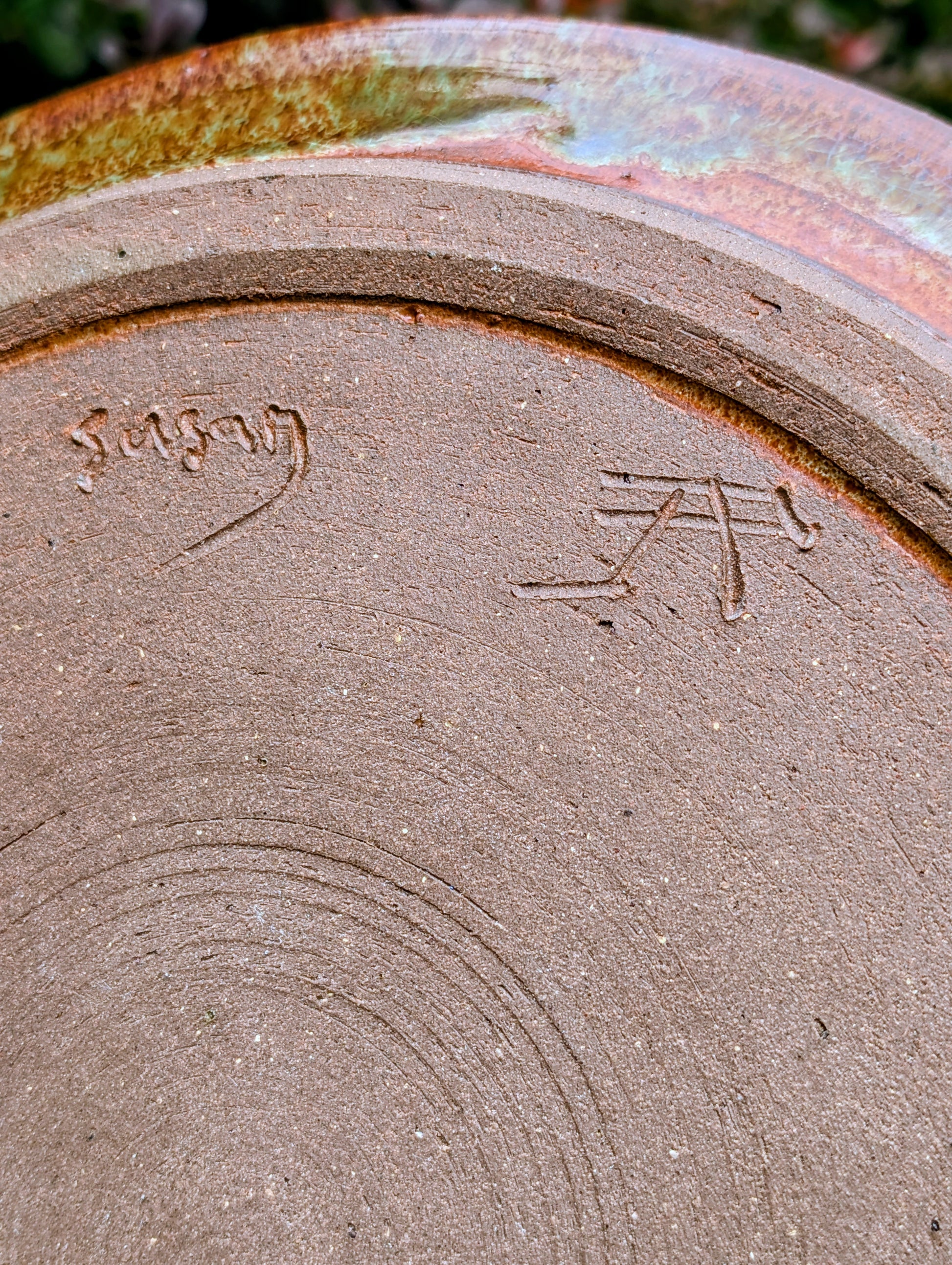 A beautifully hand-thrown studio pottery charger featuring an impressed spiral design and richly variegated moss green and rust glazes. This substantial signed stoneware piece brings timeless craftsmanship and Pacific Northwest-inspired warmth to shelves, tables, or wall displays.