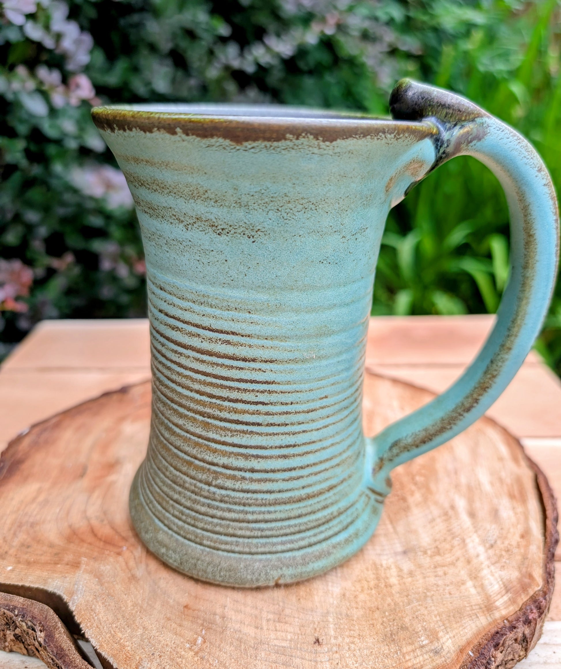 A beautifully handcrafted studio pottery tankard-style mug, wheel-thrown in Hot Springs, Arkansas and dated 2007. Its flowing turquoise, olive, and bronze glaze, generous size, and comfortable thumb-rest handle make it both a functional everyday piece and a collectible example of American studio pottery.