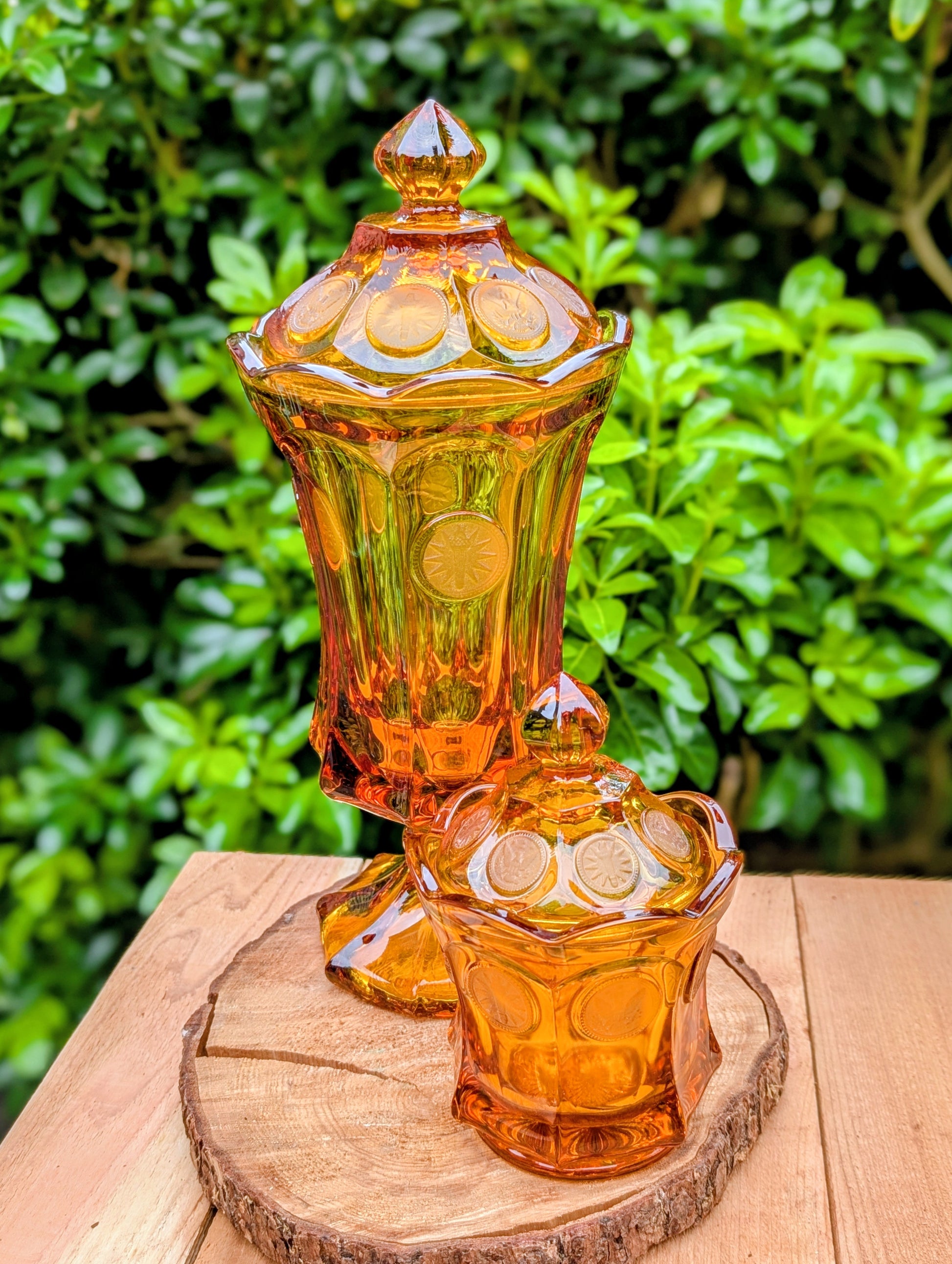 A stunning matching set of vintage Indiana Glass in the iconic Kings Crown (Coin) pattern. This coordinated amber glass collection includes a covered pedestal vase and matching covered candy dish, each with its original lid. A beautiful Mid-Century display for collectors and vintage home décor enthusiasts.