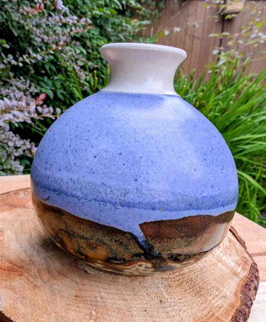 A beautifully signed studio pottery bud vase featuring a softly rounded bubble form and layered landscape-inspired glazes. Its organic silhouette and calming palette make it an elegant accent for modern, minimalist, and nature-inspired interiors.
