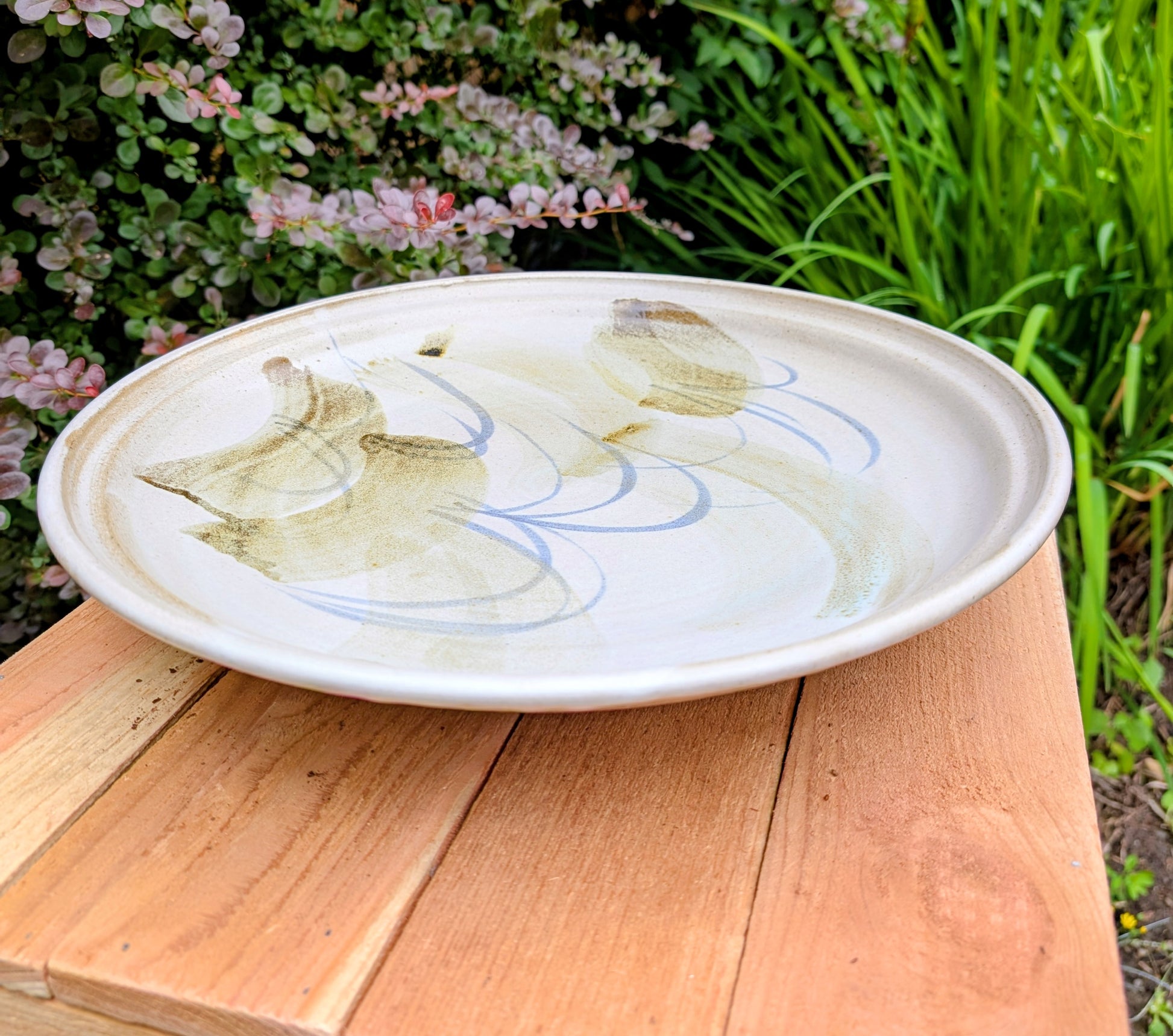 A beautifully hand-thrown studio pottery platter featuring expressive blue-gray and olive brushwork over a soft neutral glaze. Its generous size and timeless craftsmanship make it equally suited for serving, display, or as striking wall décor.