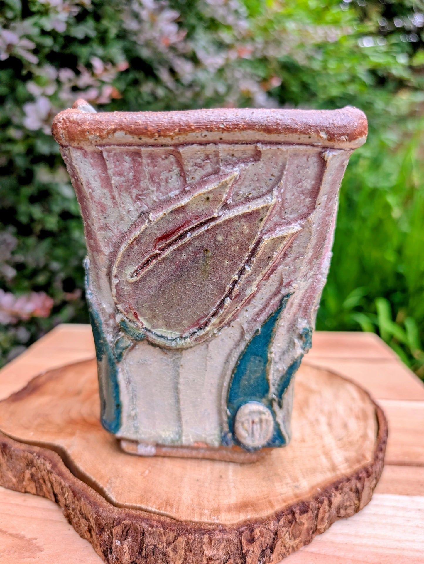 Celebrate handcrafted artistry with this handbuilt stoneware vase or cachepot featuring sculpted tulip relief panels, rich matte glazes, and an architectural four-footed form. Its organic botanical design makes it equally beautiful as a floral vessel, planter, or sculptural accent.