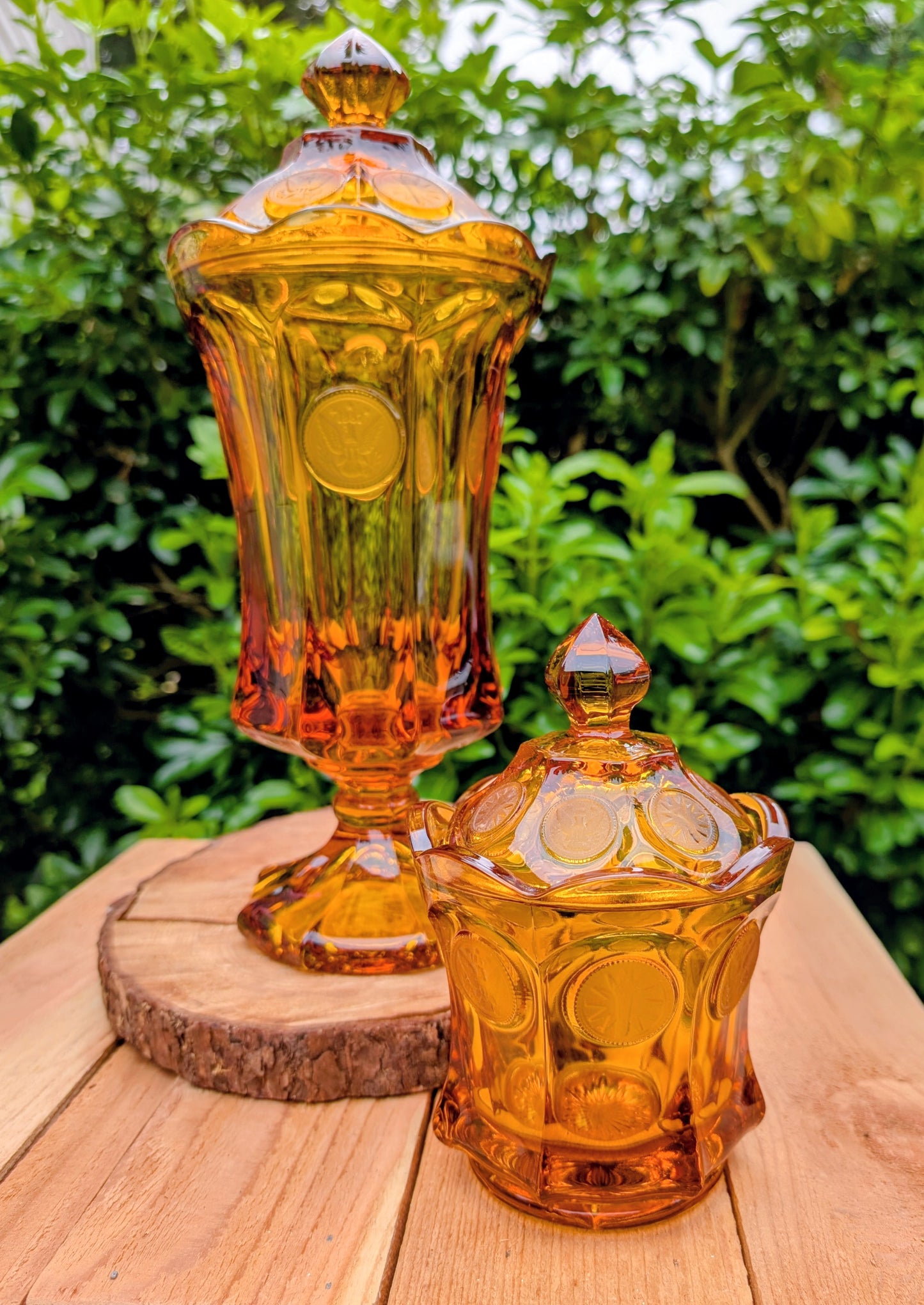 A stunning matching set of vintage Indiana Glass in the iconic Kings Crown (Coin) pattern. This coordinated amber glass collection includes a covered pedestal vase and matching covered candy dish, each with its original lid. A beautiful Mid-Century display for collectors and vintage home décor enthusiasts.