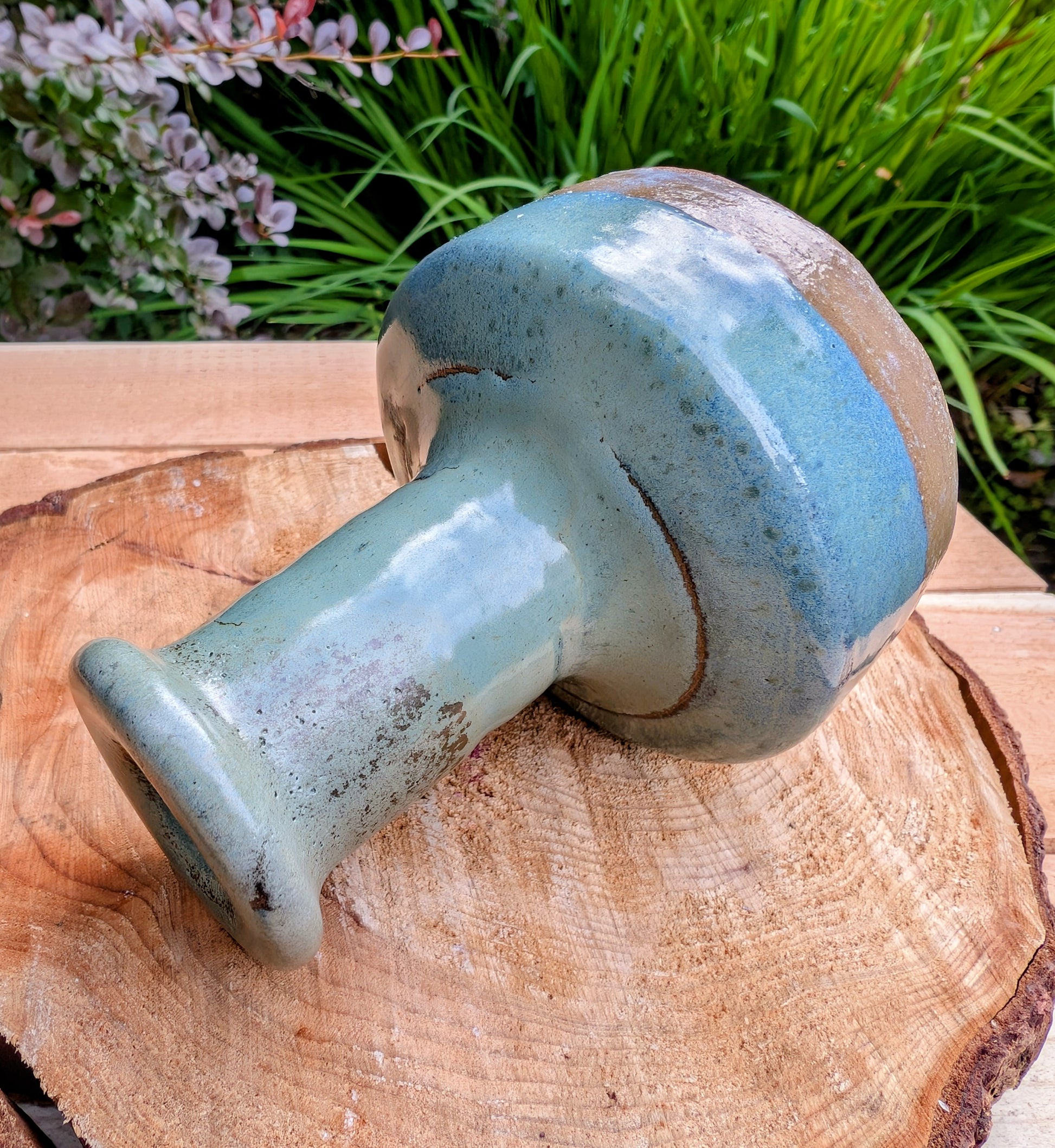 A beautifully hand-thrown studio pottery bud vase featuring a rich blue-green glaze over warm stoneware clay. Its timeless organic form makes it perfect for displaying a single bloom, dried botanicals, or as a sculptural accent in any room.
