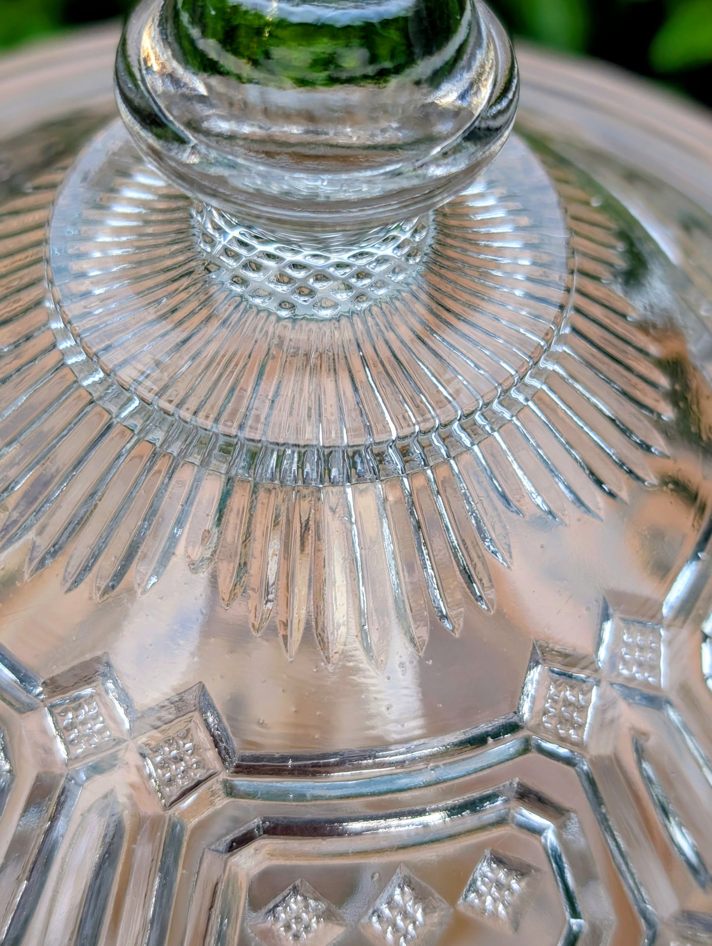 An elegant early 20th-century pressed glass covered compote featuring bold geometric Art Deco styling and a striking pedestal silhouette. Although the pedestal has visible stress cracks, the original lid, impressive scale, and architectural design make it a beautiful decorative display piece.
