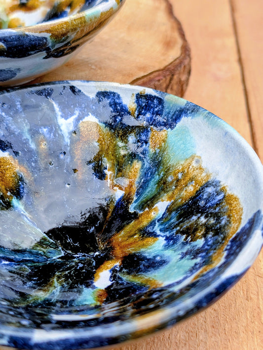 Bring handcrafted artistry to your table with this matching pair of signed studio pottery bowls. Finished with richly layered reactive glazes in cobalt blue, teal, amber, and ivory, these versatile artisan bowls are equally beautiful for entertaining or everyday display.