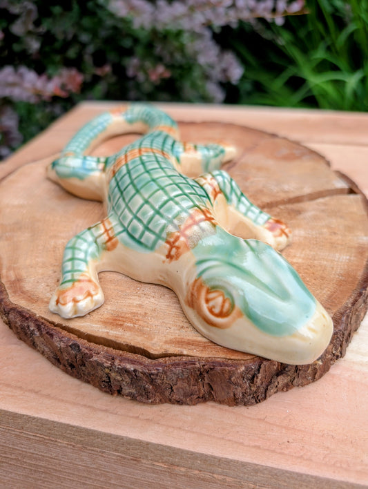 Bring a touch of whimsical European charm to your home or garden with this vintage ceramic alligator wall pocket. Featuring hand-painted green scales and a functional rear pocket for dried flowers or an air plant, it's a delightful accent for cottage-inspired interiors and nature lovers alike.