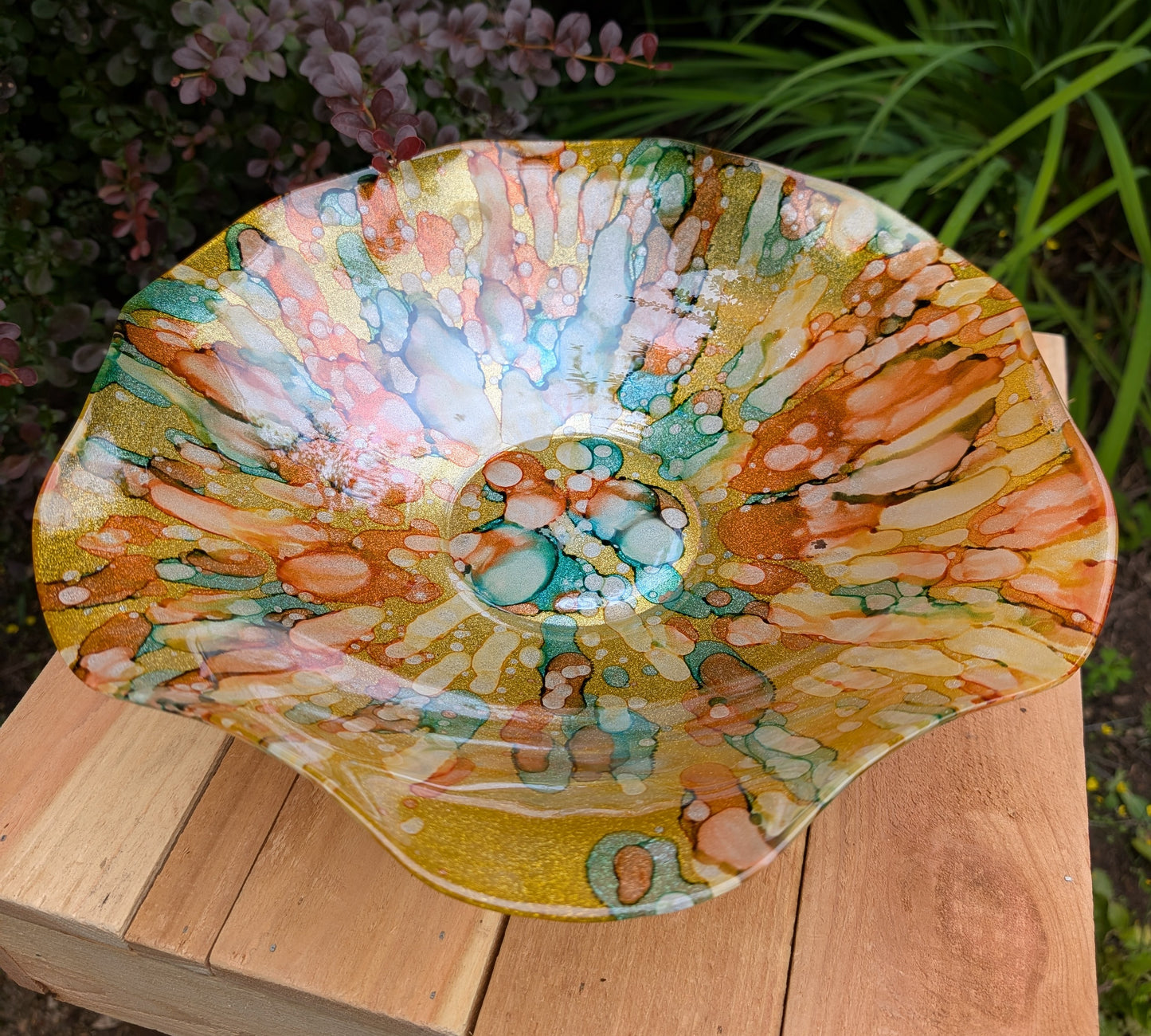 Bring color and light to your home or garden with this contemporary scalloped art glass bowl. Featuring warm golden tones accented by olive green, amber, turquoise, and shimmering metallic highlights, it serves beautifully as a centerpiece, decorative bowl, or tabletop bird bath.