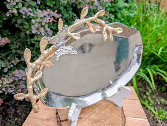 Bring the beauty of the forest indoors with this elegant cast aluminum serving platter featuring sculpted gold-tone branch handles and a delicate butterfly accent. Equally suited for entertaining or displaying seasonal décor, this nature-inspired piece blends organic artistry with timeless metallic finishes.