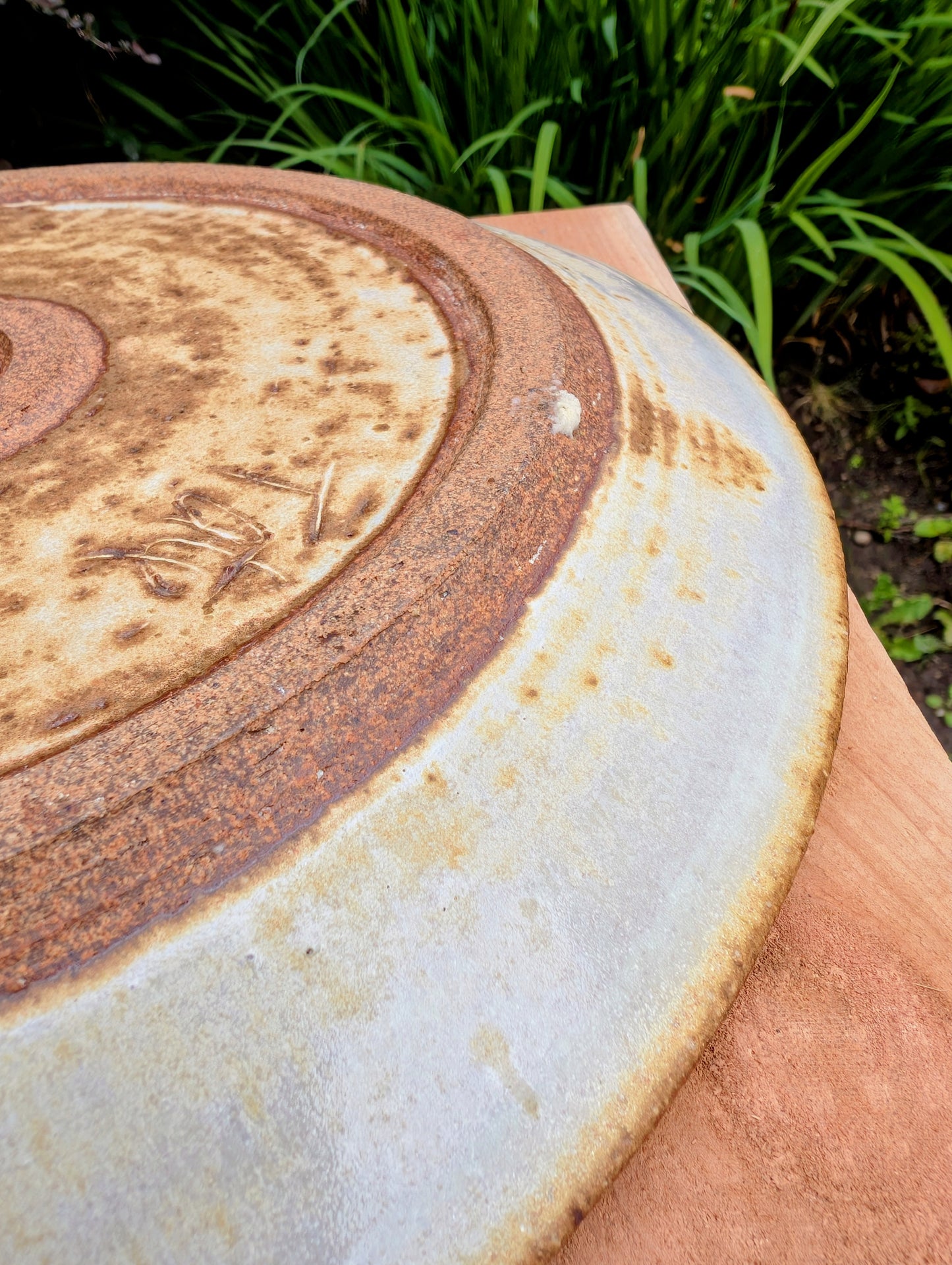 A striking hand-thrown studio pottery platter featuring an expressive cream, maroon, and olive glaze composition with visible throwing rings and an incised artist signature. Beautiful as both a decorative wall display and a functional serving piece, it embodies the warmth and craftsmanship of contemporary American studio ceramics.