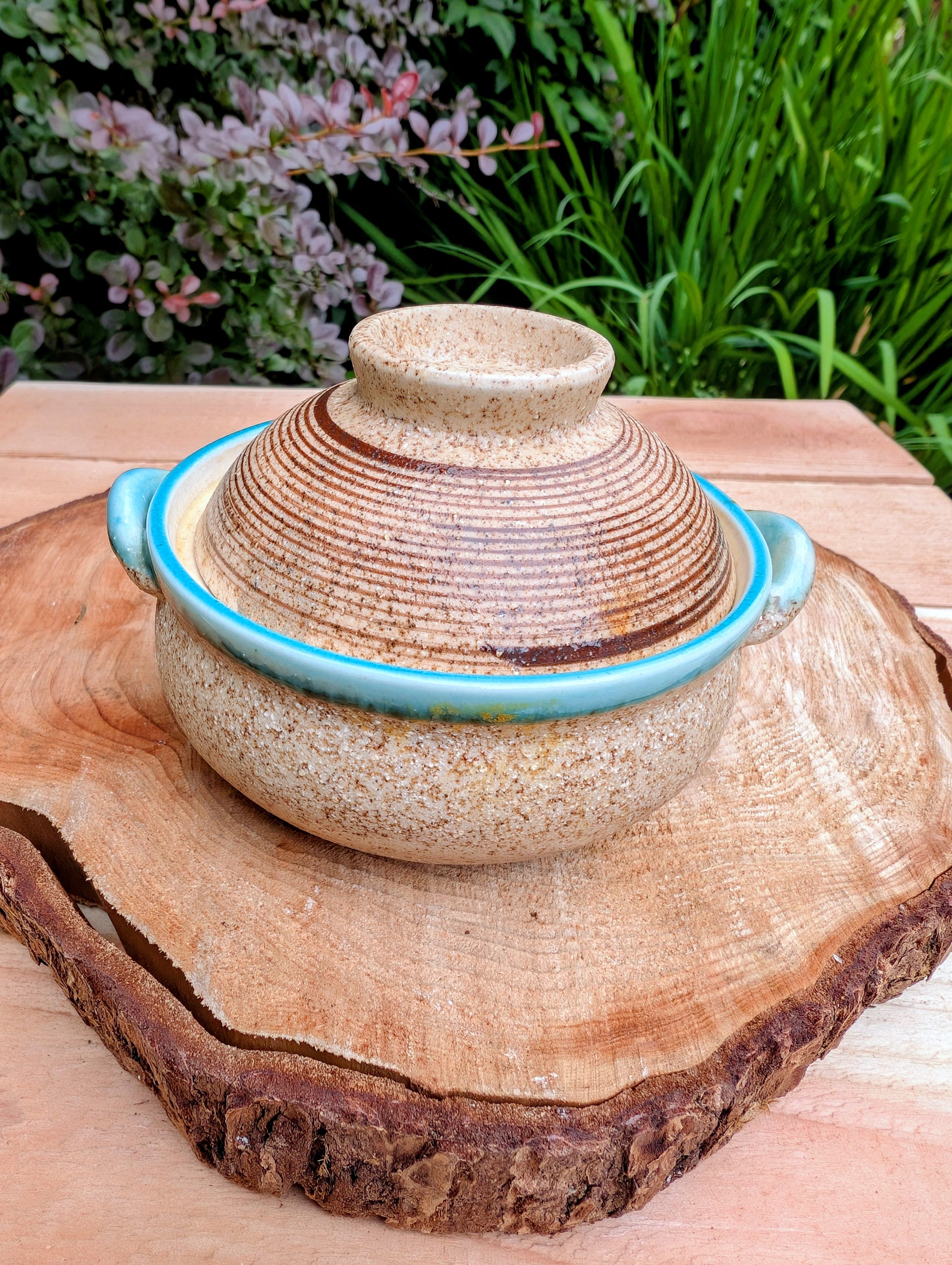 A beautifully handcrafted studio pottery bowl featuring a warm speckled stoneware exterior, vibrant turquoise glazed interior, and matching ribbed lid. Its compact size and organic design make it perfect for serving small dishes or displaying as a timeless piece of artisan pottery.