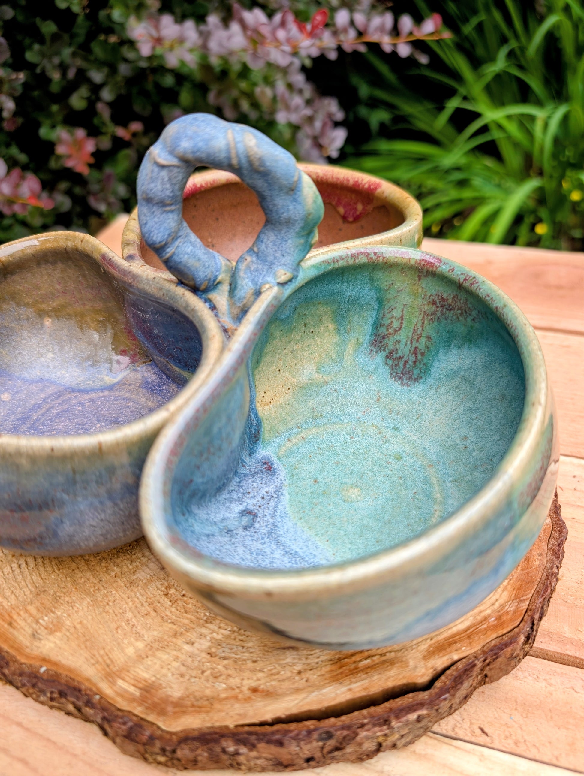 Beautifully handcrafted and artist signed, this three-bowl stoneware condiment server combines sculptural artistry with everyday functionality. Finished in layered seafoam, aqua, moss, and earthy glazes, it brings timeless craftsmanship and Pacific Northwest-inspired beauty to entertaining.