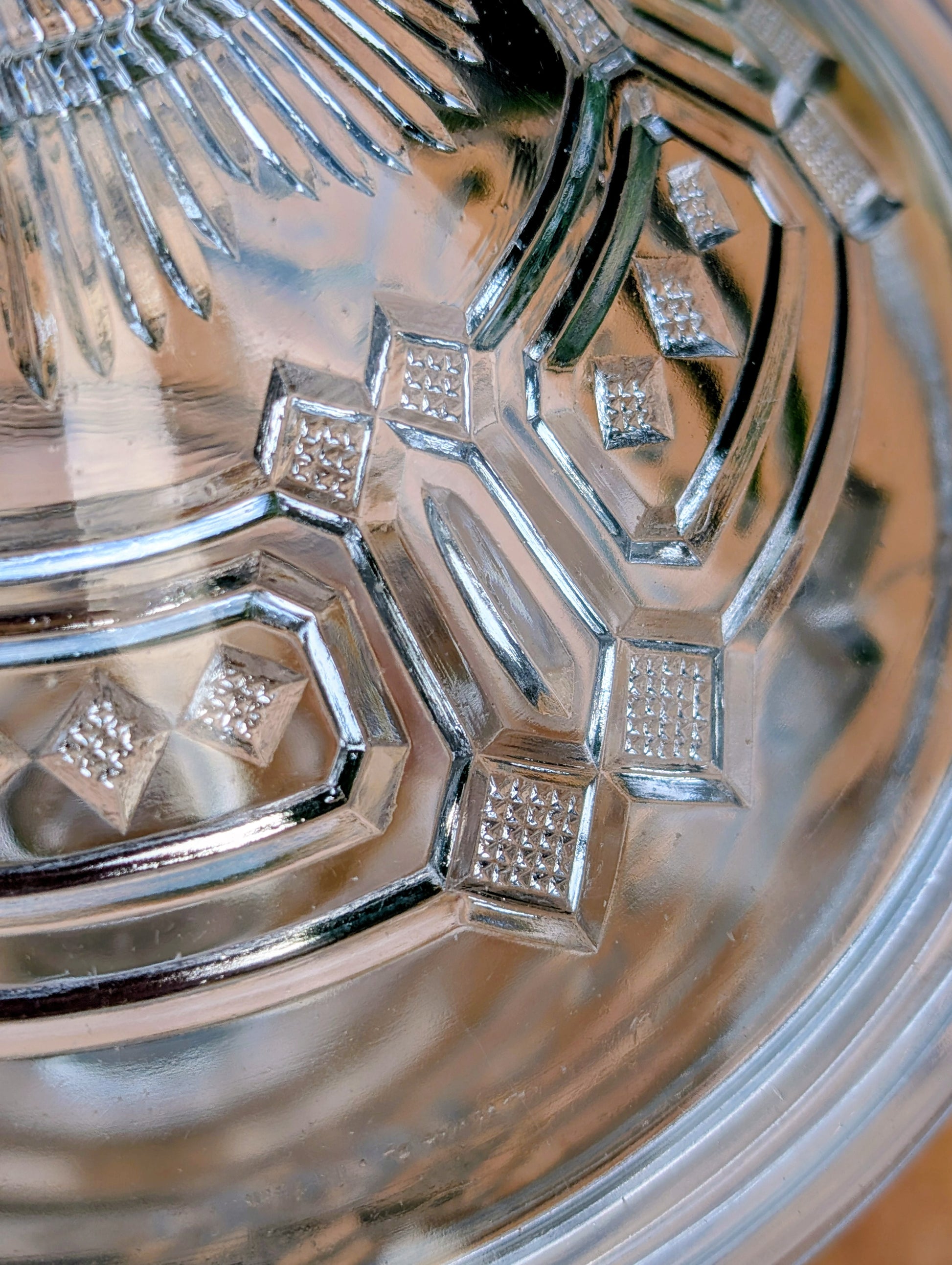 An elegant early 20th-century pressed glass covered compote featuring bold geometric Art Deco styling and a striking pedestal silhouette. Although the pedestal has visible stress cracks, the original lid, impressive scale, and architectural design make it a beautiful decorative display piece.