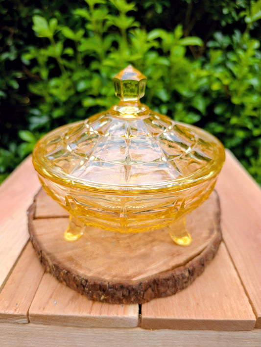 Bring warm vintage charm to your home with this beautiful Tiara Exclusives Constellation covered candy dish in the sought-after Yellow Mist color. Produced by Indiana Glass during the 1970s, its geometric star pattern and golden glow make it a timeless piece for entertaining or display.