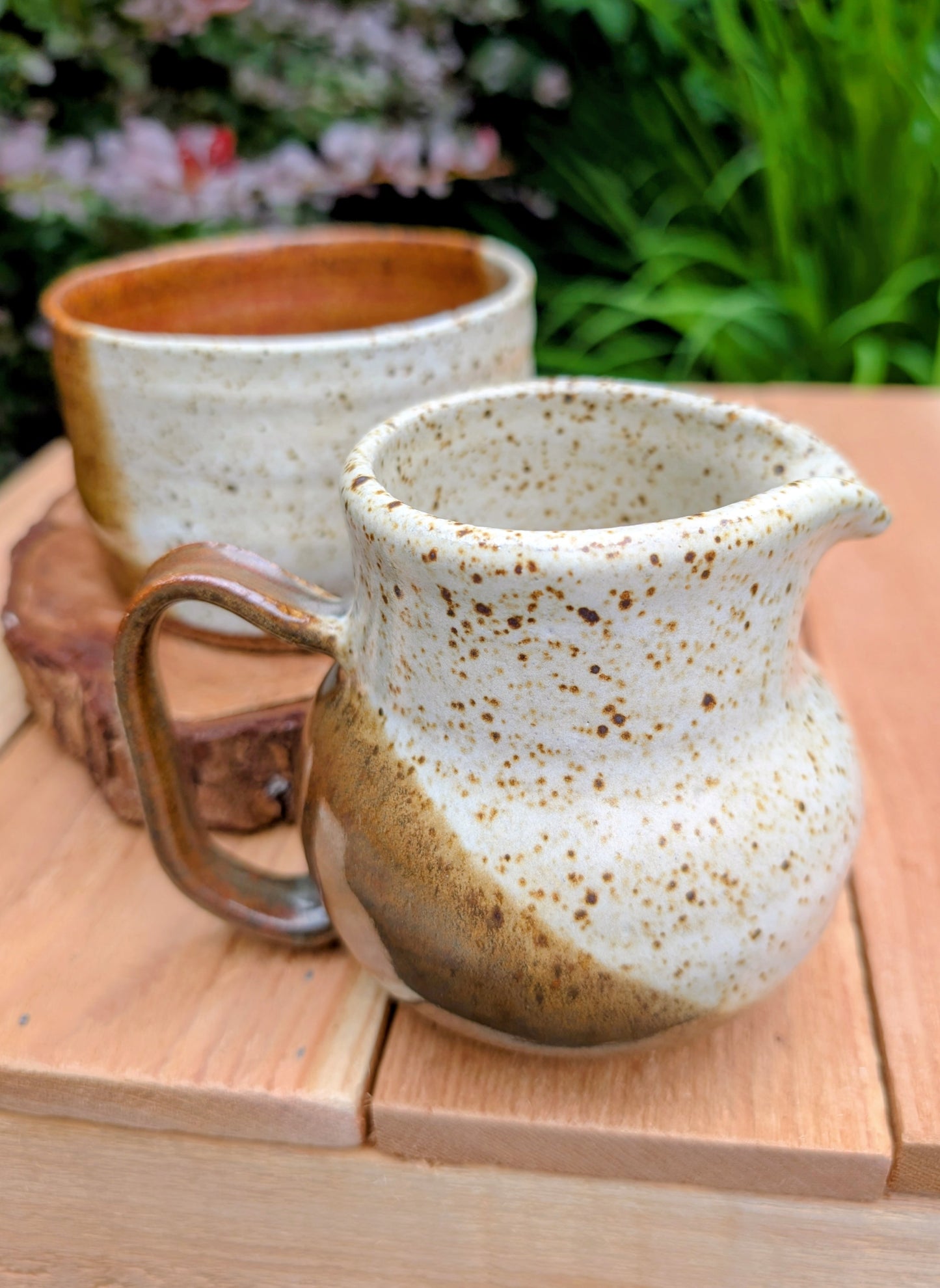 Bring handcrafted warmth to your table with this signed studio pottery creamer and sugar bowl set. Finished in a beautiful speckled cream glaze with flowing olive-brown accents, this artisan stoneware pair blends rustic craftsmanship with timeless everyday function.