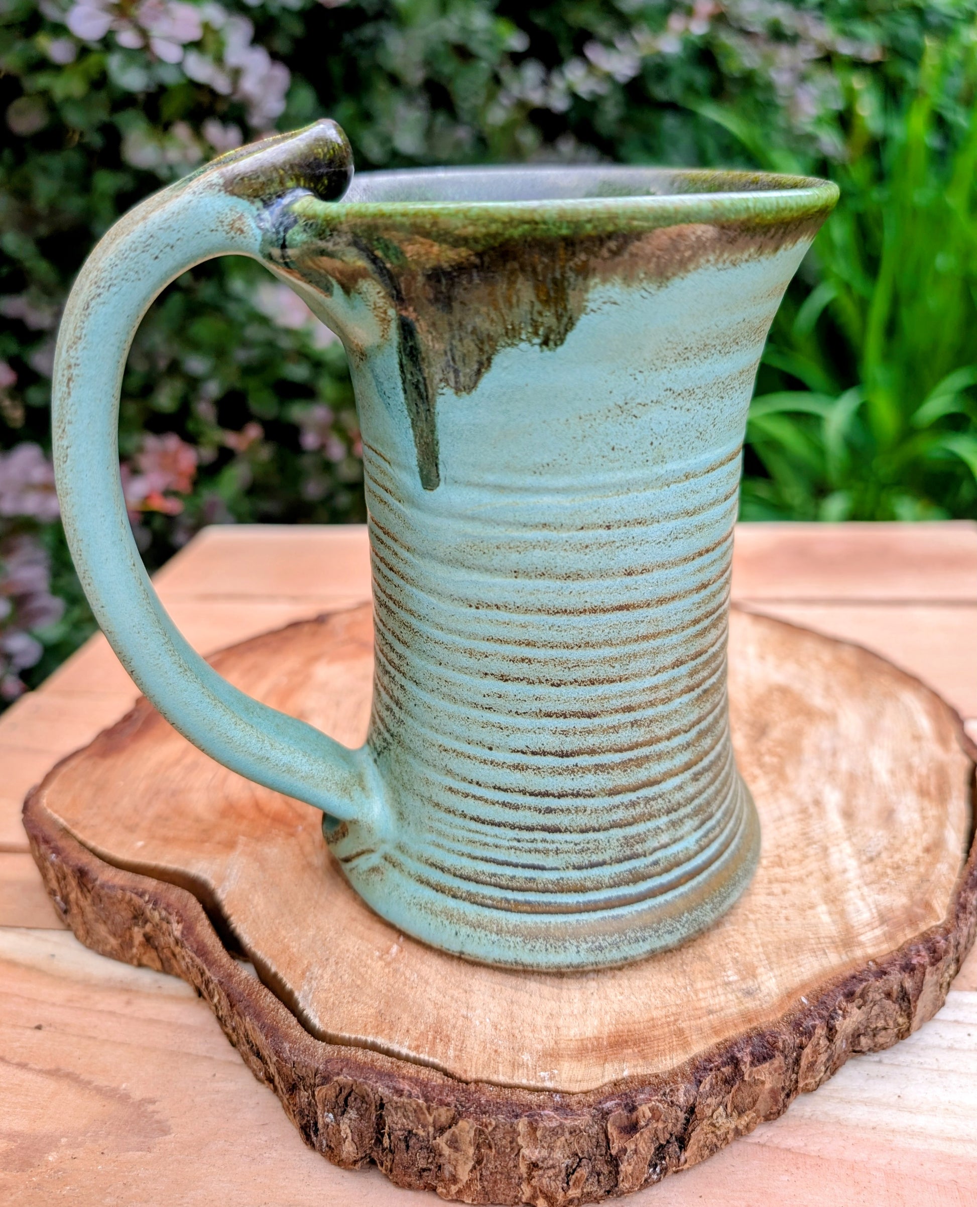 A beautifully handcrafted studio pottery tankard-style mug, wheel-thrown in Hot Springs, Arkansas and dated 2007. Its flowing turquoise, olive, and bronze glaze, generous size, and comfortable thumb-rest handle make it both a functional everyday piece and a collectible example of American studio pottery.