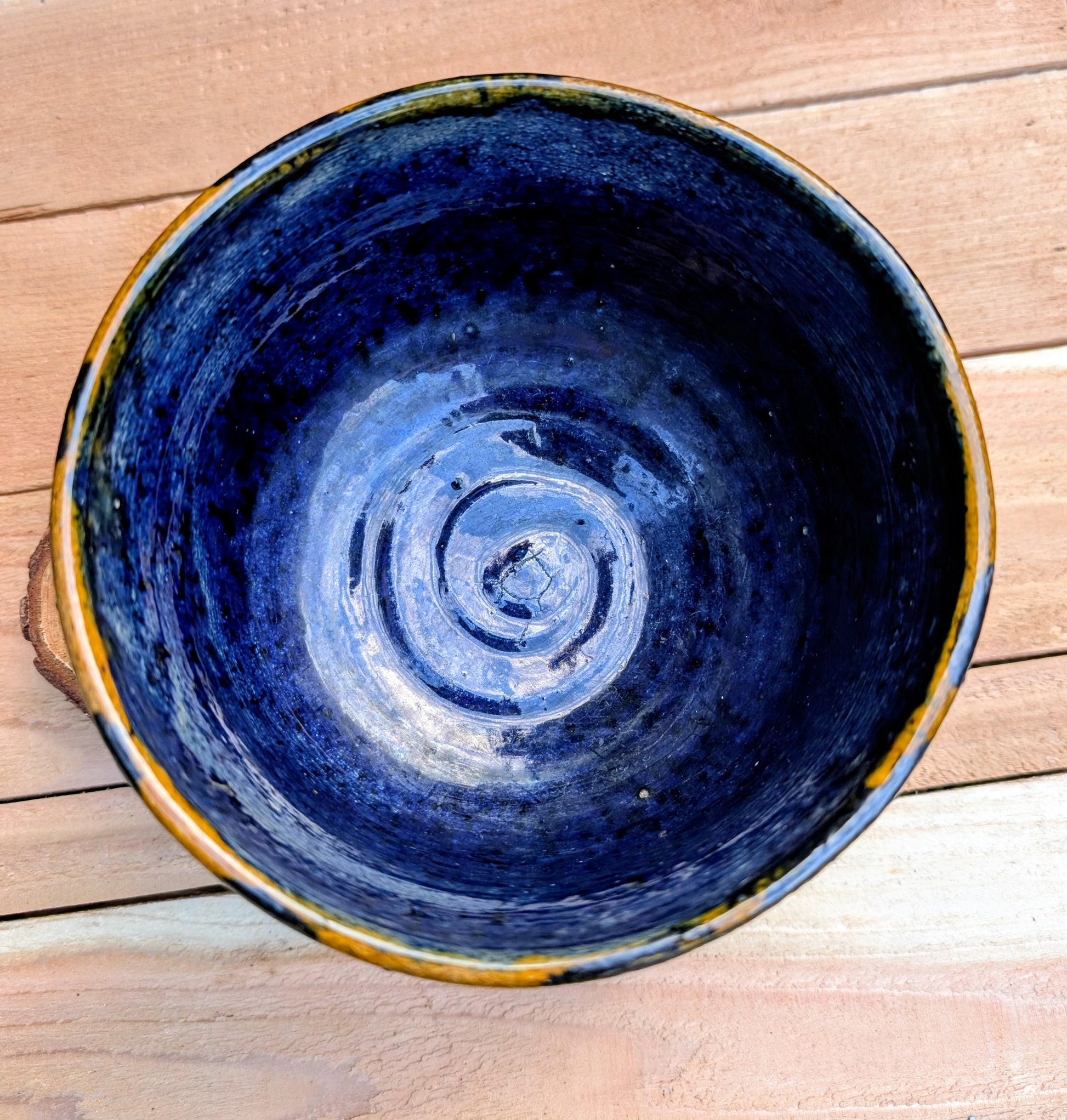 A beautifully hand-thrown studio pottery bowl featuring a rich cobalt blue interior, earthy ochre exterior, and expressive black drip glaze. Its timeless craftsmanship and organic design make it equally suited for serving, display, or adding artisan character to any Pacific Northwest-inspired home.