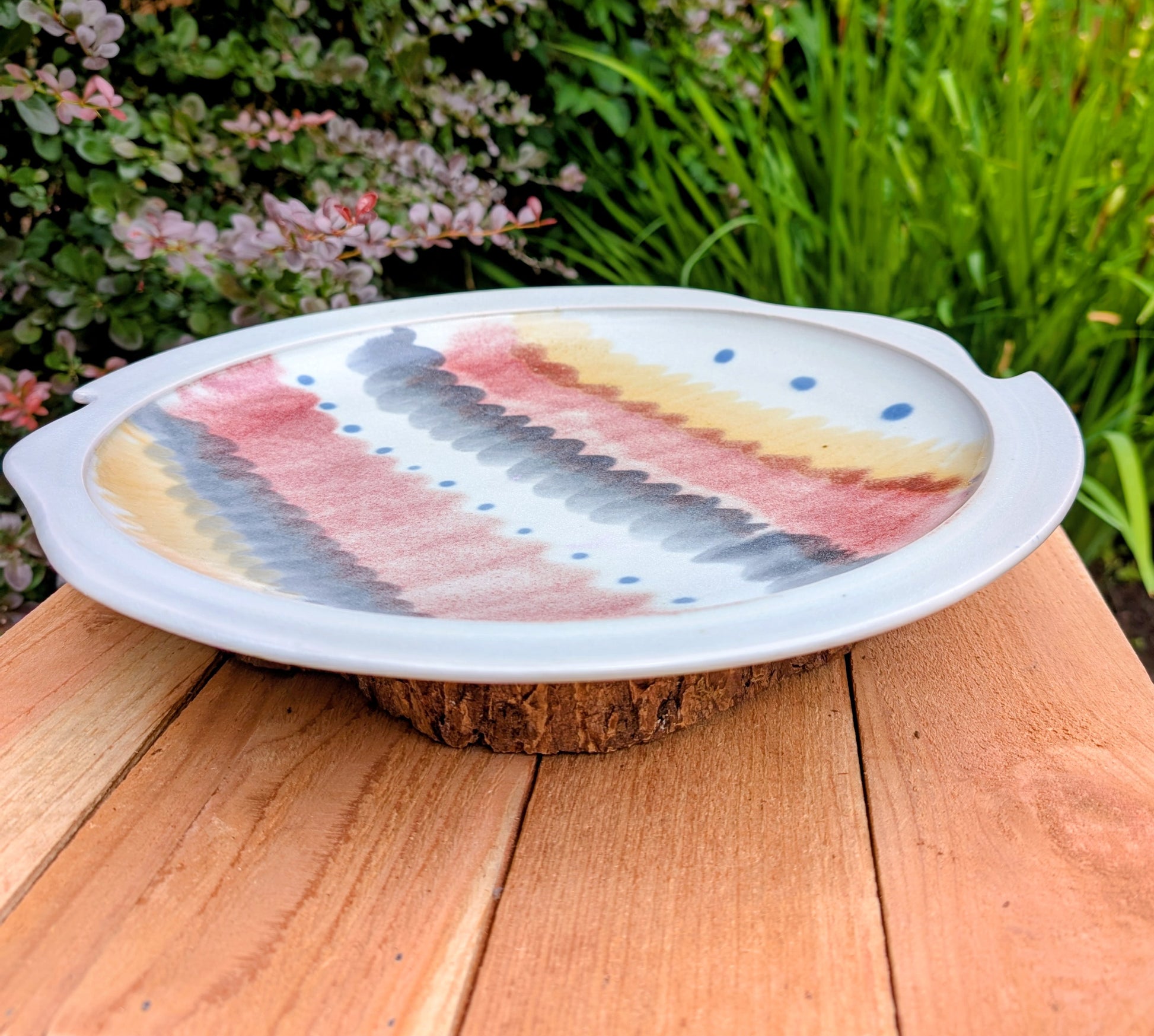 A beautifully handcrafted 14-inch studio pottery platter featuring layered abstract decoration in soft blue-gray, dusty pink, cream, and cobalt accents. Equally stunning as a serving piece or decorative display charger, this artisan-made platter brings timeless craftsmanship to modern living.