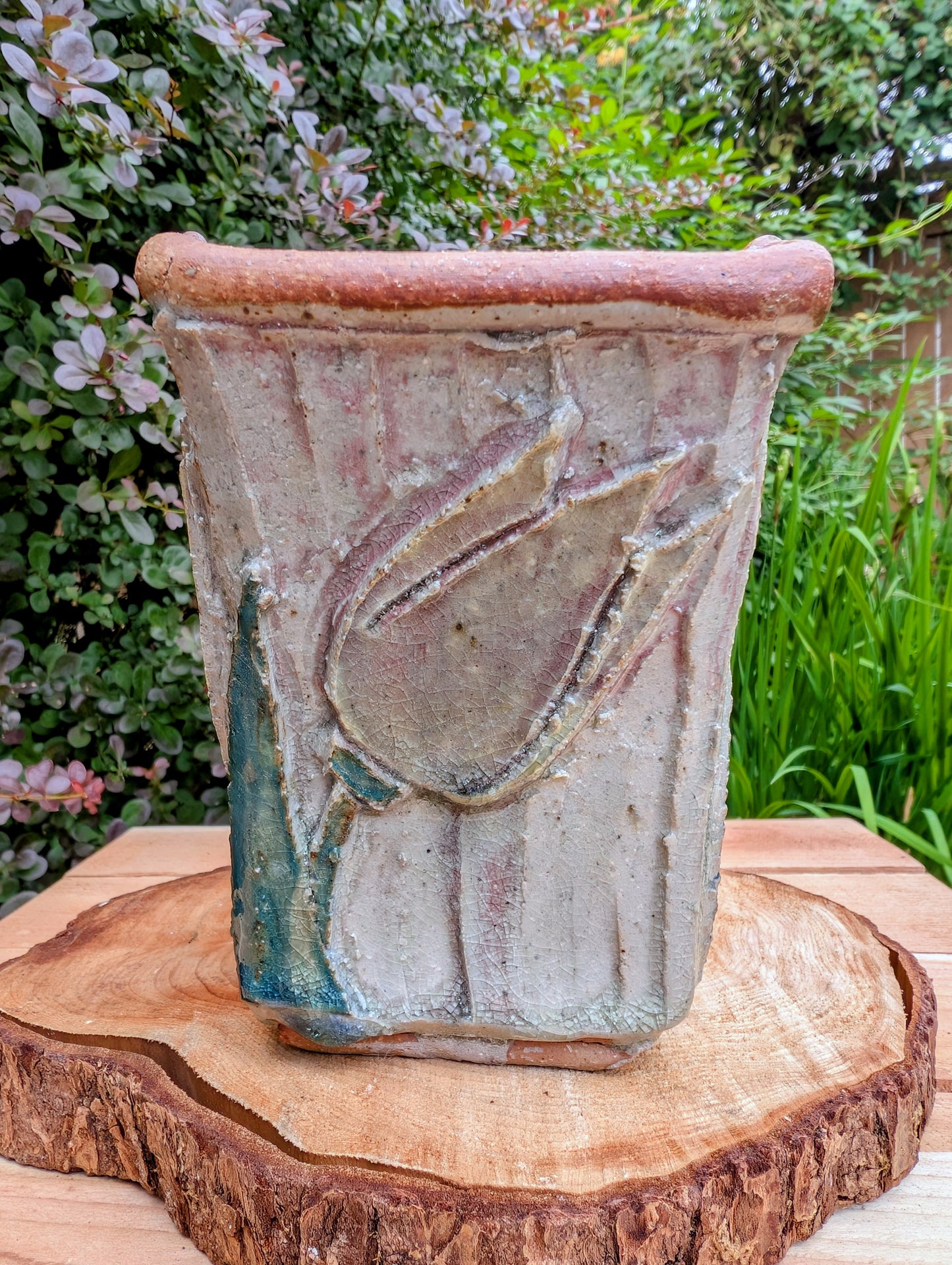 Celebrate handcrafted artistry with this handbuilt stoneware vase or cachepot featuring sculpted tulip relief panels, rich matte glazes, and an architectural four-footed form. Its organic botanical design makes it equally beautiful as a floral vessel, planter, or sculptural accent.