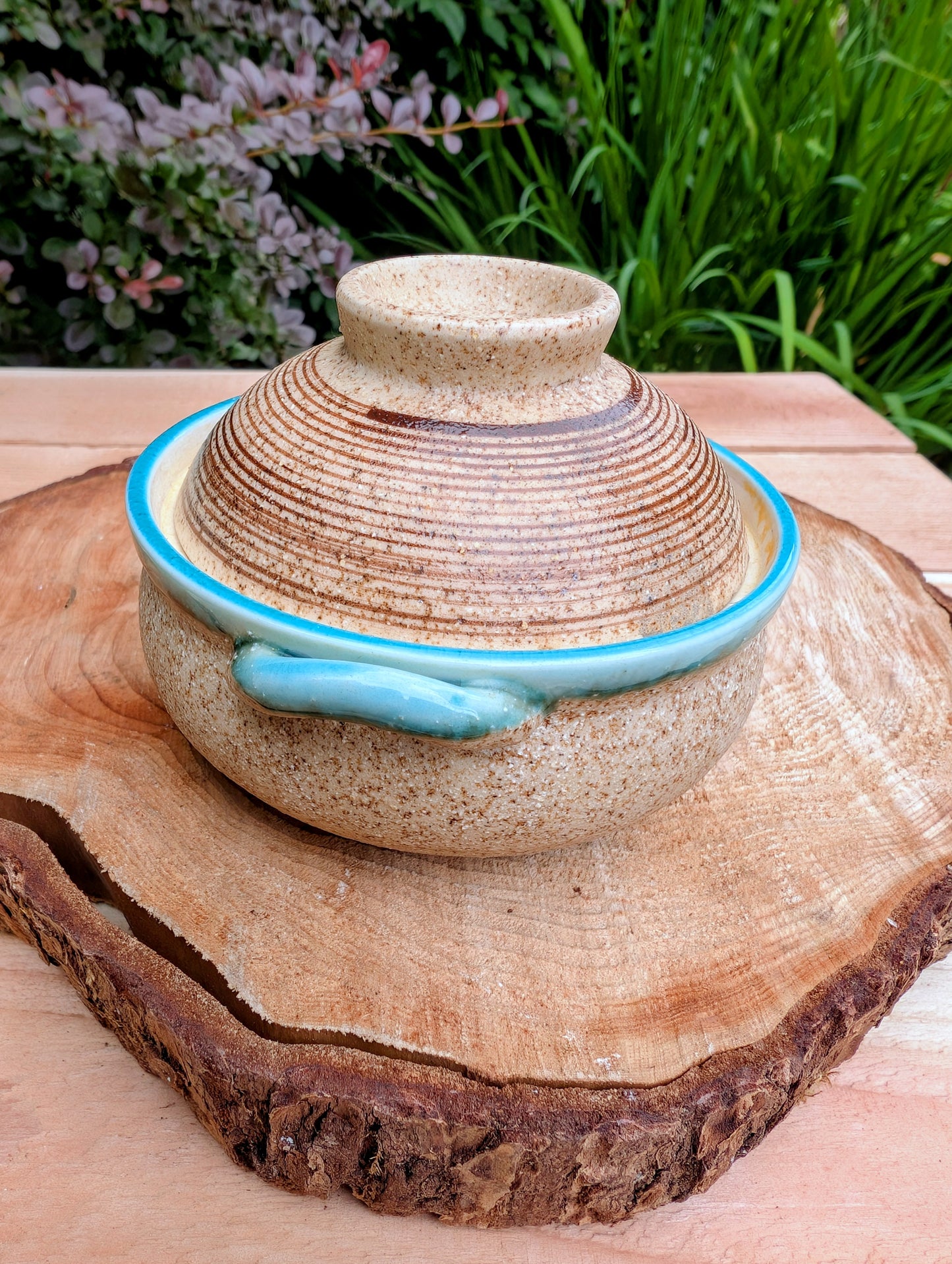 A beautifully handcrafted studio pottery bowl featuring a warm speckled stoneware exterior, vibrant turquoise glazed interior, and matching ribbed lid. Its compact size and organic design make it perfect for serving small dishes or displaying as a timeless piece of artisan pottery.