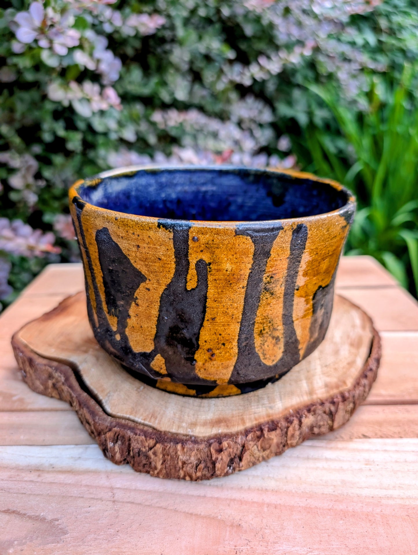 A beautifully hand-thrown studio pottery bowl featuring a rich cobalt blue interior, earthy ochre exterior, and expressive black drip glaze. Its timeless craftsmanship and organic design make it equally suited for serving, display, or adding artisan character to any Pacific Northwest-inspired home.