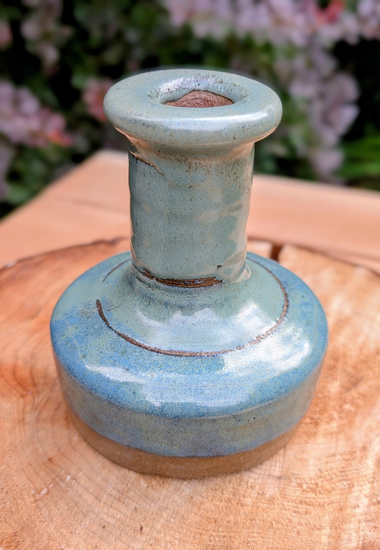A beautifully hand-thrown studio pottery bud vase featuring a rich blue-green glaze over warm stoneware clay. Its timeless organic form makes it perfect for displaying a single bloom, dried botanicals, or as a sculptural accent in any room.