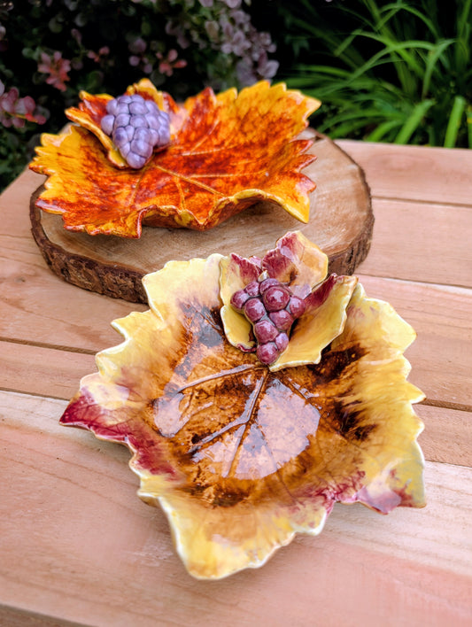 Celebrate the warmth of the harvest season with this charming set of two vintage Lamplite Ceramics leaf-shaped dishes from Fresno, California. Featuring sculpted grape clusters and rich autumn-inspired glazes, these decorative trays bring timeless vineyard style to seasonal entertaining and home décor.