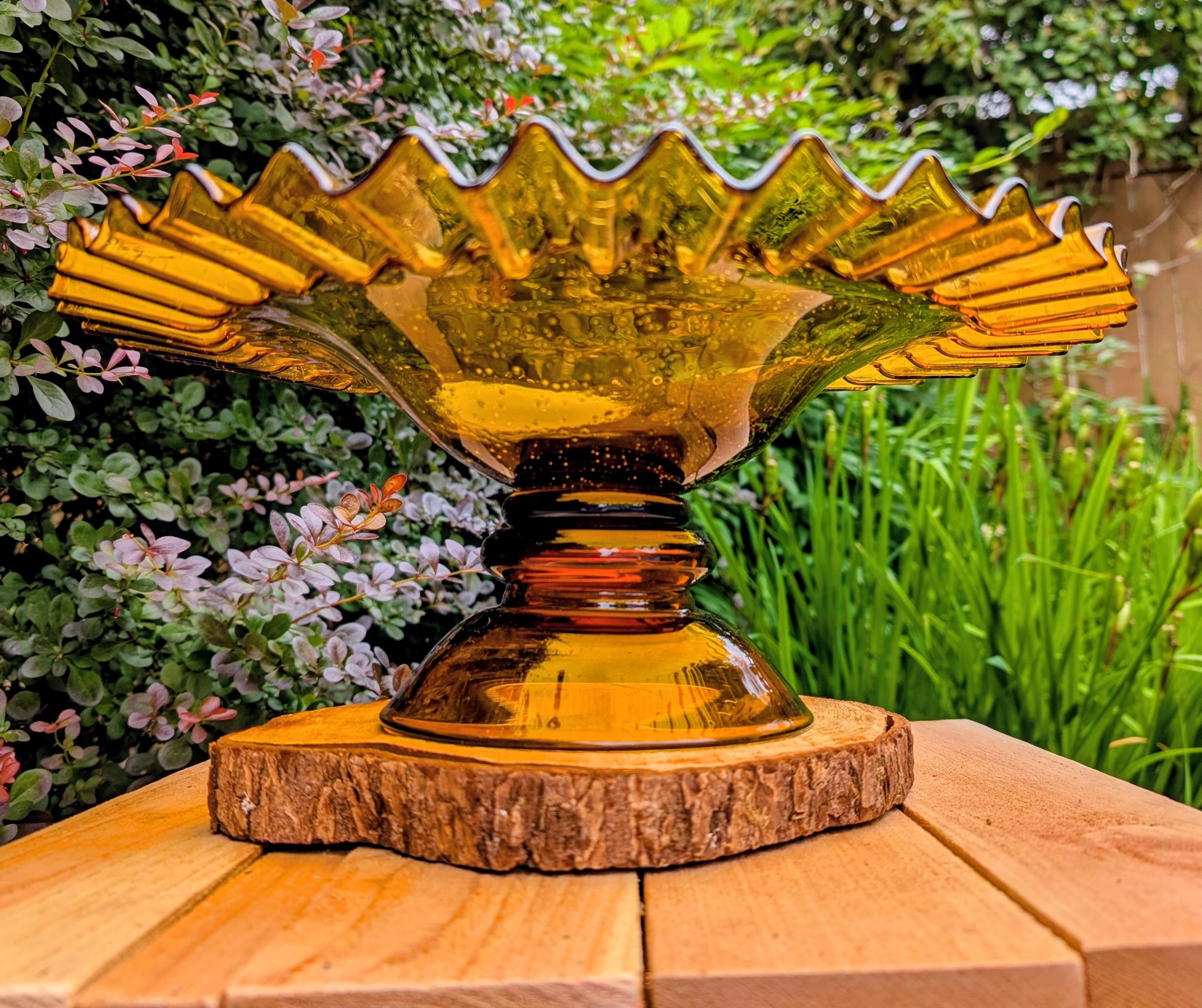 Bring warm vintage charm to your home with this large amber pressed glass pedestal console bowl, estimated to have been made by Indiana Glass during the 1960s–1970s. Its dramatic ruffled rim and generous size make it a beautiful centerpiece for seasonal displays, fruit, florals, or decorative accents throughout the year.